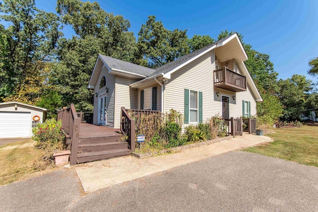 view of front of house featuring a balcony, an outbuilding, and a front yard