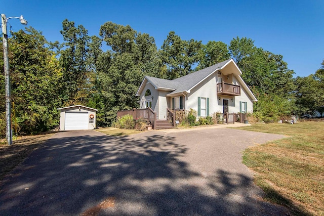 view of front of home with an outbuilding, a balcony, a detached garage, driveway, and a front lawn