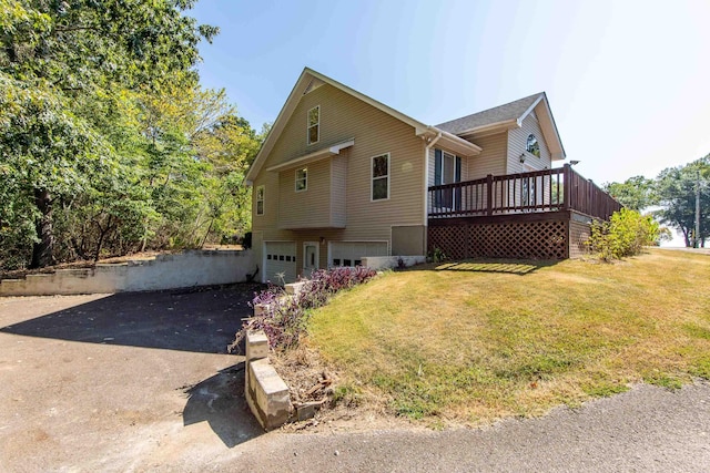 view of front of house featuring an attached garage, aphalt driveway, a front lawn, and a wooden deck