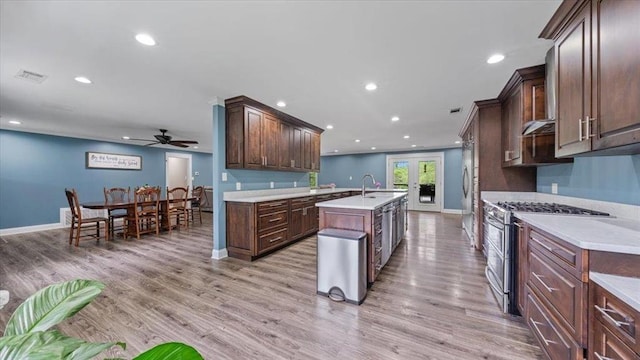 kitchen featuring appliances with stainless steel finishes, light countertops, a kitchen island with sink, and light wood finished floors