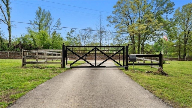 view of gate with fence and a lawn