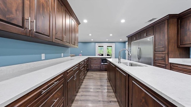 kitchen featuring recessed lighting, built in refrigerator, wood finished floors, a sink, and light countertops