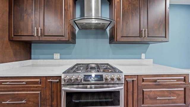 kitchen with dark brown cabinetry, stainless steel gas range oven, and wall chimney exhaust hood