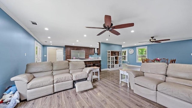 living area featuring recessed lighting, visible vents, light wood-style floors, ornamental molding, and baseboards