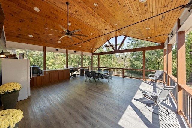 unfurnished sunroom with a healthy amount of sunlight, wooden ceiling, ceiling fan, and vaulted ceiling