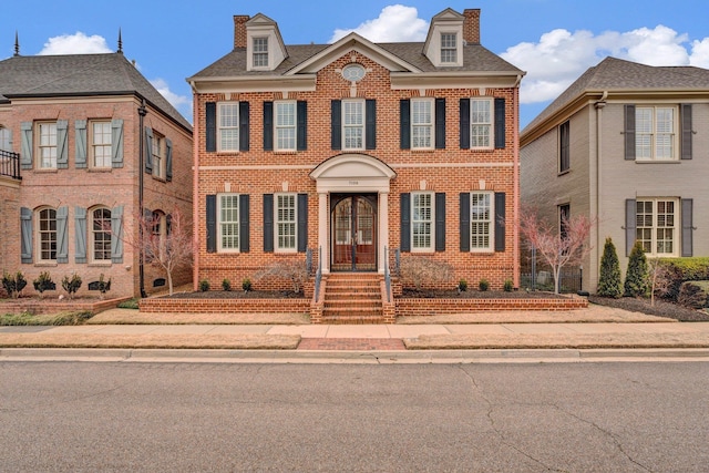 colonial house featuring brick siding and a chimney