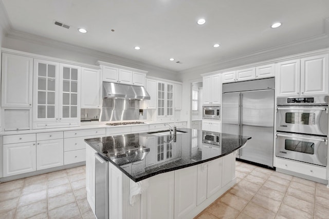 kitchen featuring visible vents, built in appliances, under cabinet range hood, white cabinetry, and a sink