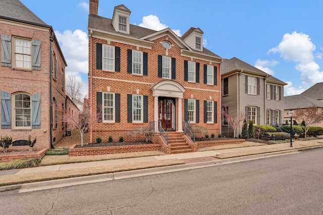 colonial-style house with a shingled roof and brick siding