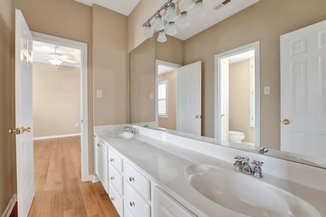 full bathroom with toilet, visible vents, a sink, and wood finished floors