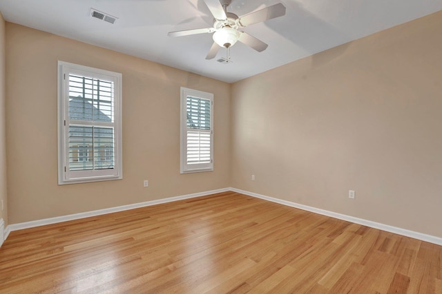 spare room featuring light wood-type flooring, baseboards, visible vents, and a ceiling fan