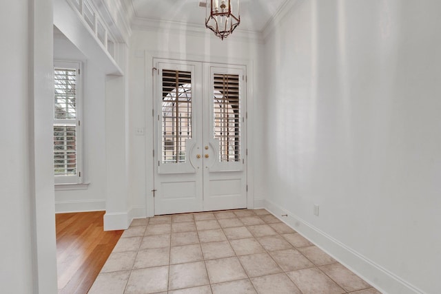 entrance foyer with a notable chandelier, baseboards, crown molding, and french doors