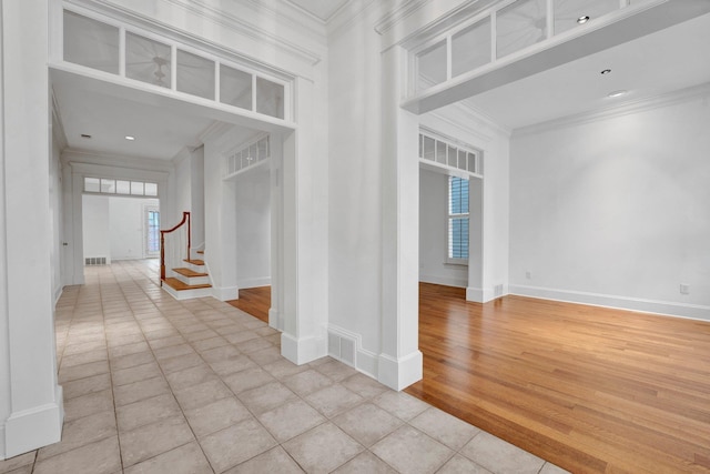 unfurnished room with ornamental molding, a healthy amount of sunlight, and stairway