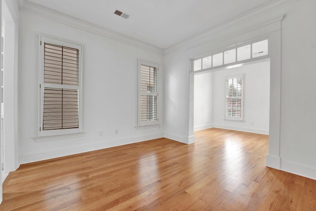 empty room with visible vents, crown molding, light wood-style flooring, and baseboards