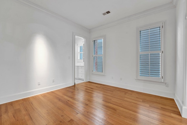 unfurnished room featuring light wood finished floors, visible vents, and crown molding