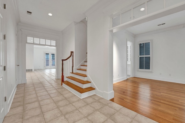 foyer entrance featuring visible vents, crown molding, baseboards, and stairs