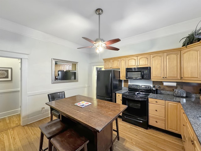 kitchen with a breakfast bar area, crown molding, light wood finished floors, and black appliances