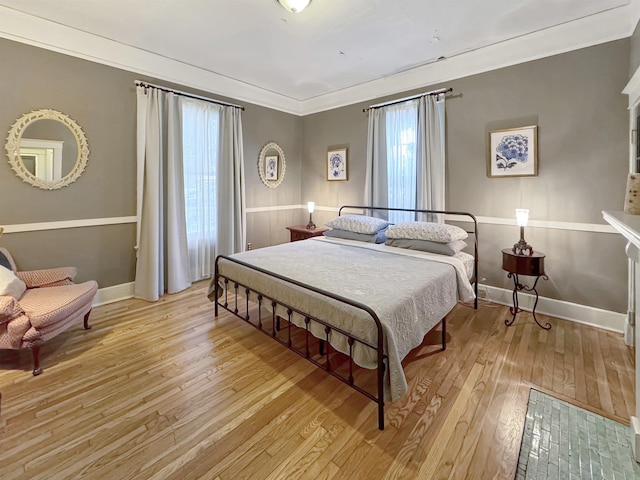 bedroom with baseboards, crown molding, and light wood finished floors