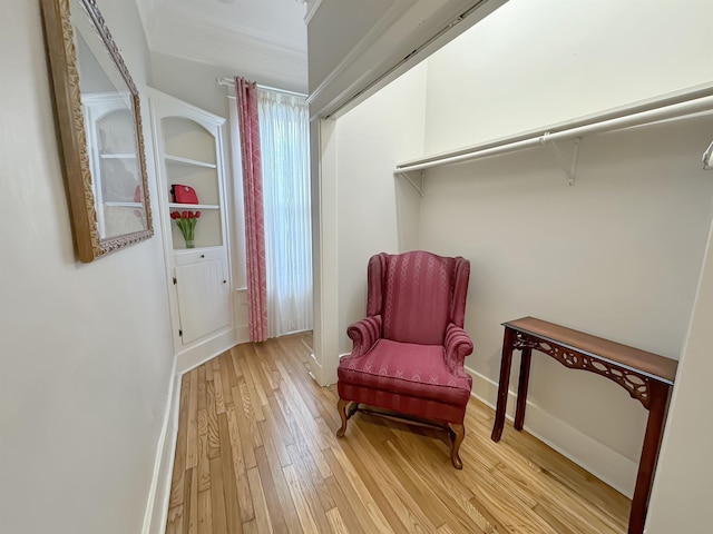 sitting room featuring crown molding, light wood-style flooring, and baseboards