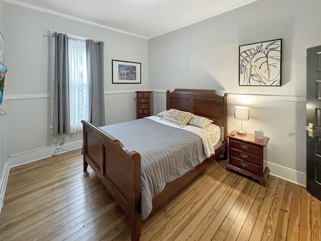 bedroom with ornamental molding, light wood-style flooring, and baseboards