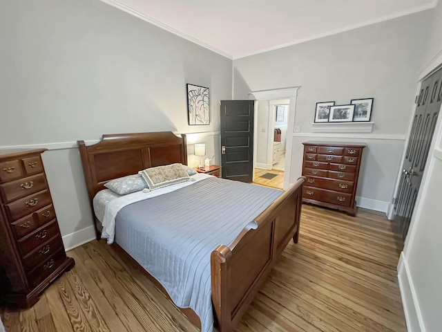 bedroom with light wood finished floors, baseboards, and crown molding