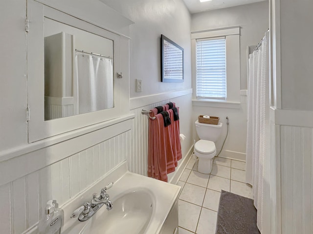 bathroom featuring a shower with shower curtain, toilet, wainscoting, tile patterned flooring, and vanity