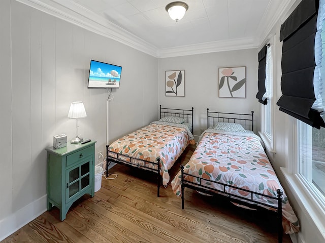 bedroom featuring ornamental molding, wood finished floors, and baseboards