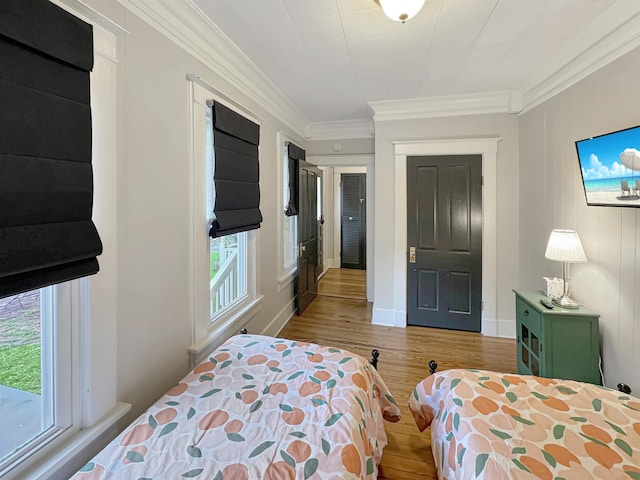 bedroom featuring ornamental molding, multiple windows, wood finished floors, and baseboards