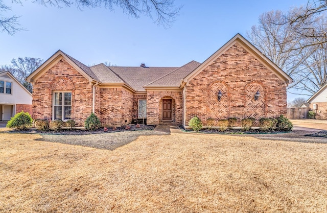 ranch-style house featuring brick siding, a front yard, and a shingled roof