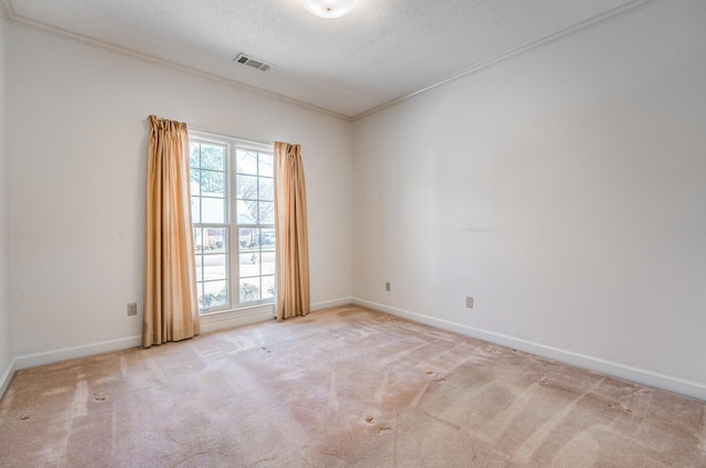 spare room with carpet, plenty of natural light, visible vents, and crown molding