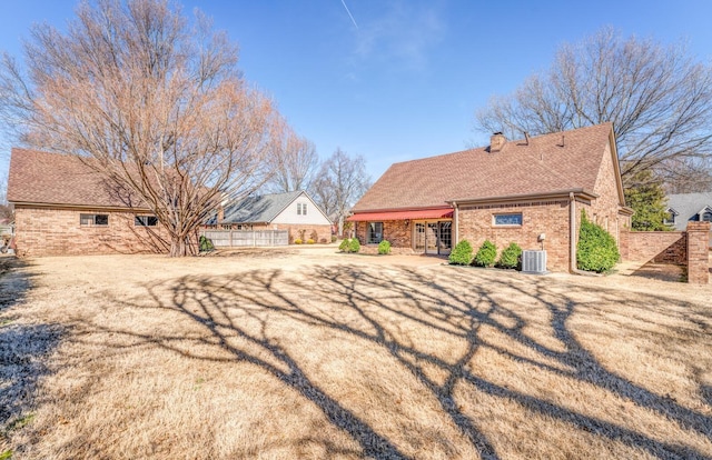 rear view of house featuring french doors, brick siding, roof with shingles, a chimney, and central air condition unit