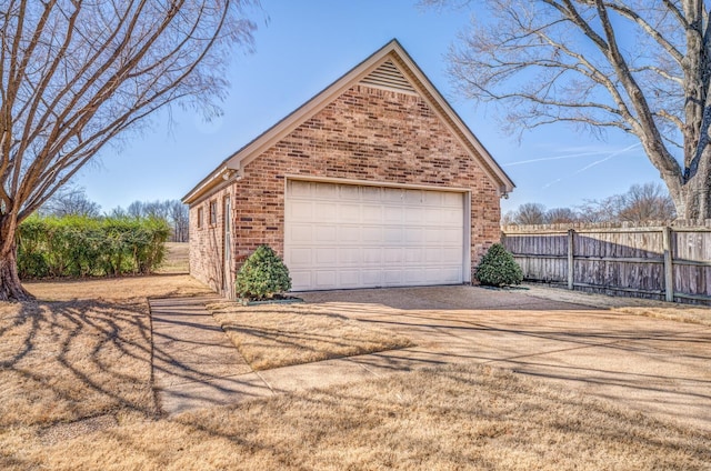 garage featuring driveway and fence