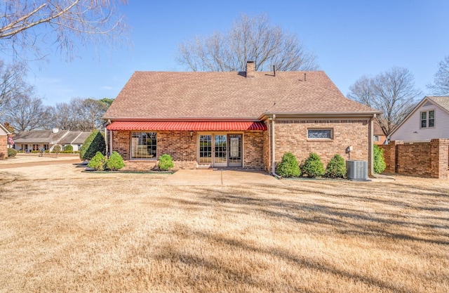 rear view of house with french doors, brick siding, a chimney, and a shingled roof