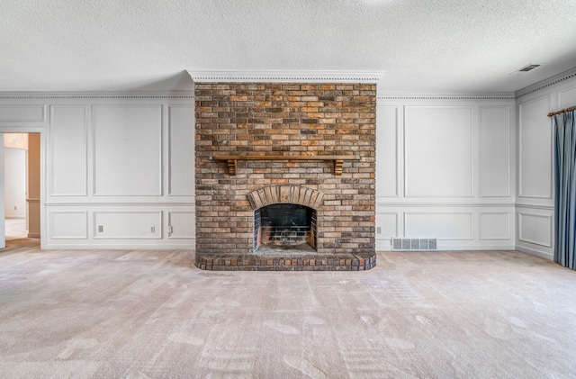 unfurnished living room with carpet floors, visible vents, a decorative wall, and a fireplace