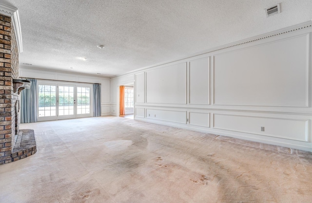 unfurnished living room featuring visible vents, crown molding, a textured ceiling, carpet flooring, and a decorative wall