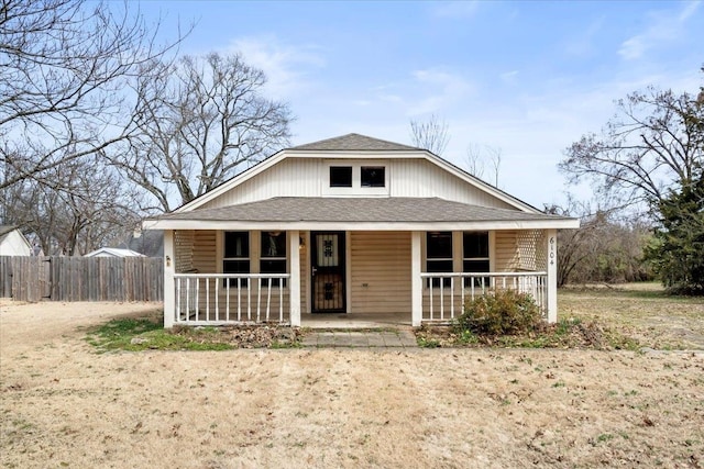 bungalow-style home featuring a shingled roof, covered porch, and fence