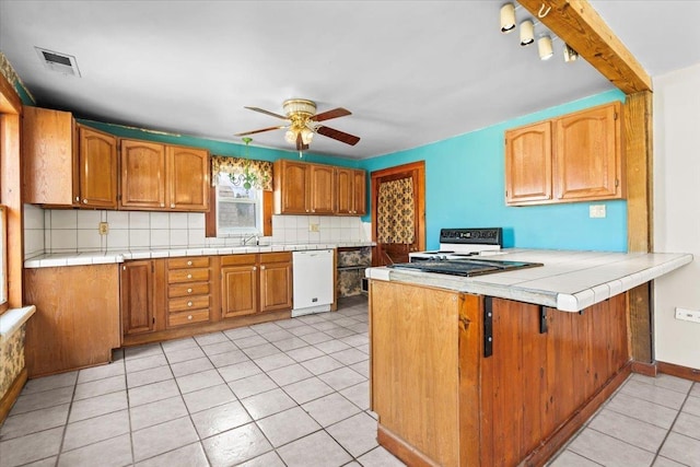 kitchen with white appliances, visible vents, decorative backsplash, a peninsula, and a sink