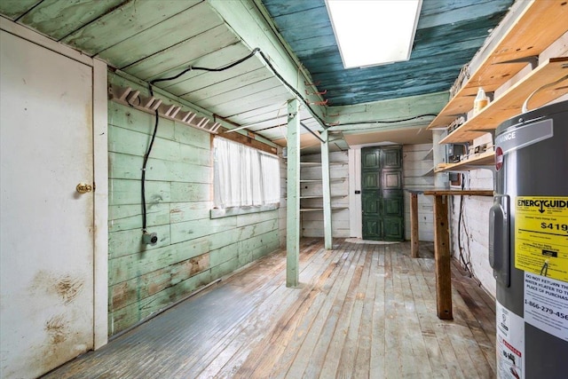 interior space featuring wood walls, hardwood / wood-style floors, and electric water heater