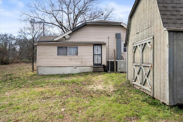 back of house with an outbuilding, a yard, central air condition unit, entry steps, and a barn