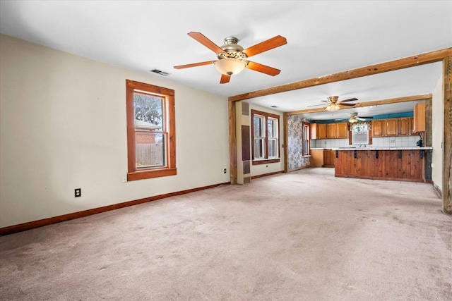 unfurnished living room featuring beam ceiling, visible vents, light carpet, and baseboards