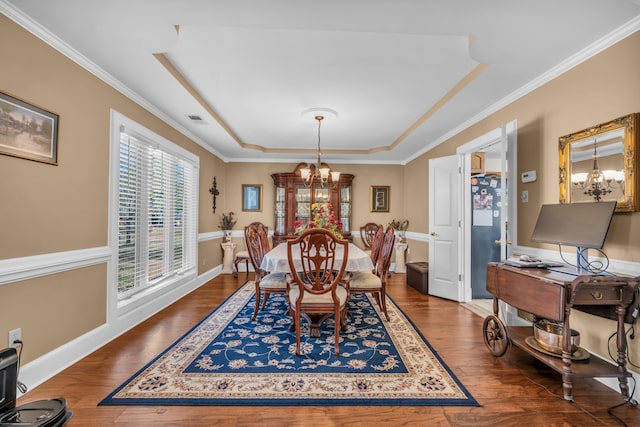 dining room featuring hardwood / wood-style floors, visible vents, a raised ceiling, and a notable chandelier