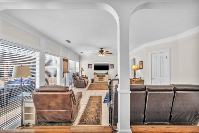 living area featuring arched walkways, crown molding, visible vents, a ceiling fan, and tile patterned flooring