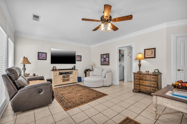 living room featuring light tile patterned floors, a ceiling fan, visible vents, washer / dryer, and crown molding