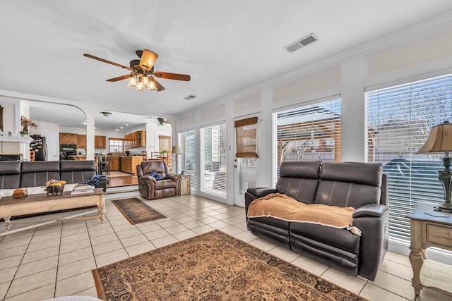 living room with light tile patterned floors, ceiling fan, ornamental molding, and visible vents