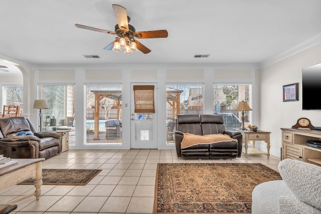 living room with light tile patterned floors, ceiling fan, visible vents, and crown molding