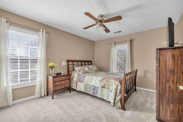 bedroom with carpet floors, multiple windows, visible vents, and a textured ceiling