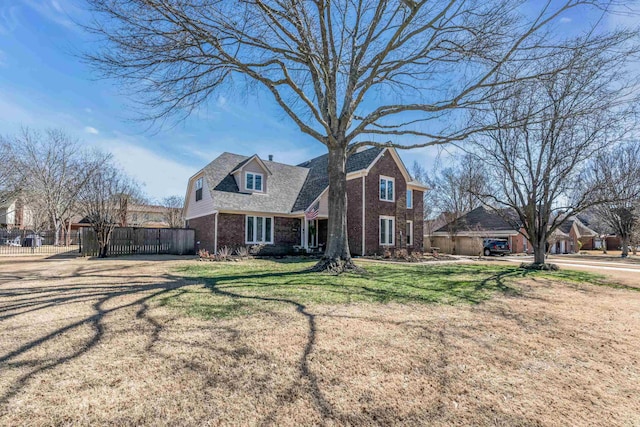 view of front facade featuring brick siding, a front yard, and fence