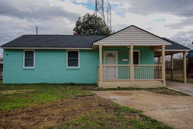 view of front of home with covered porch, roof with shingles, brick siding, and a front lawn