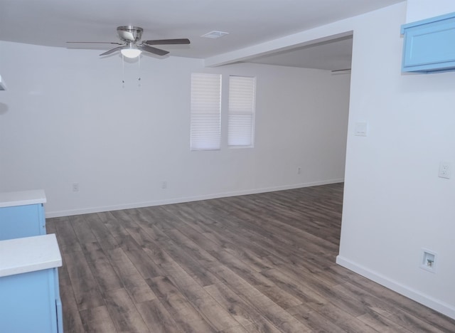 unfurnished room with dark wood-style floors, visible vents, baseboards, and a ceiling fan