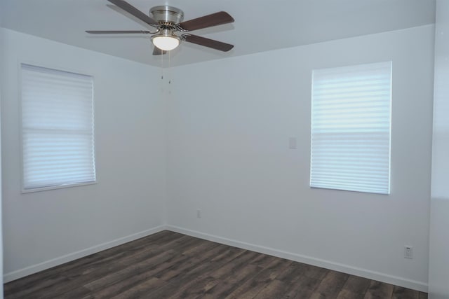 empty room featuring plenty of natural light, dark wood finished floors, and baseboards