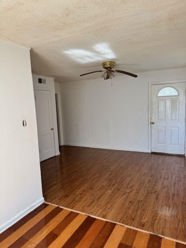 interior space with visible vents, a textured ceiling, baseboards, and wood finished floors